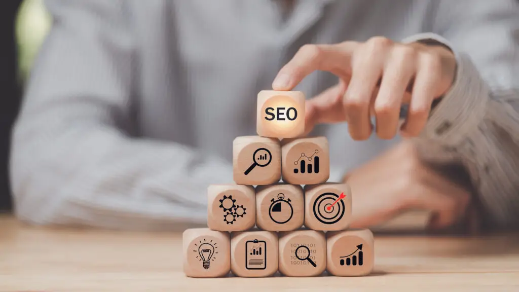 Person stacking SEO cubes on wooden table.